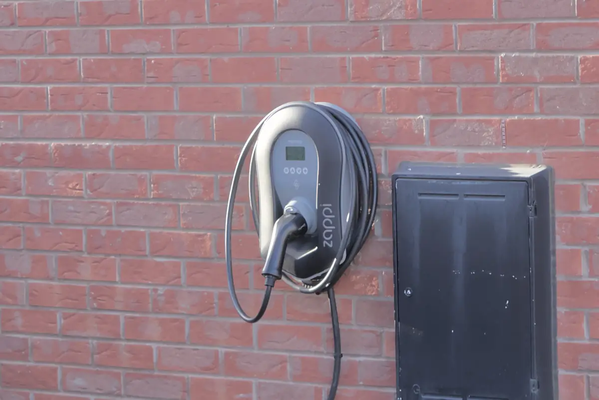 Home electric car charger with a coiled cable on a brick house wall