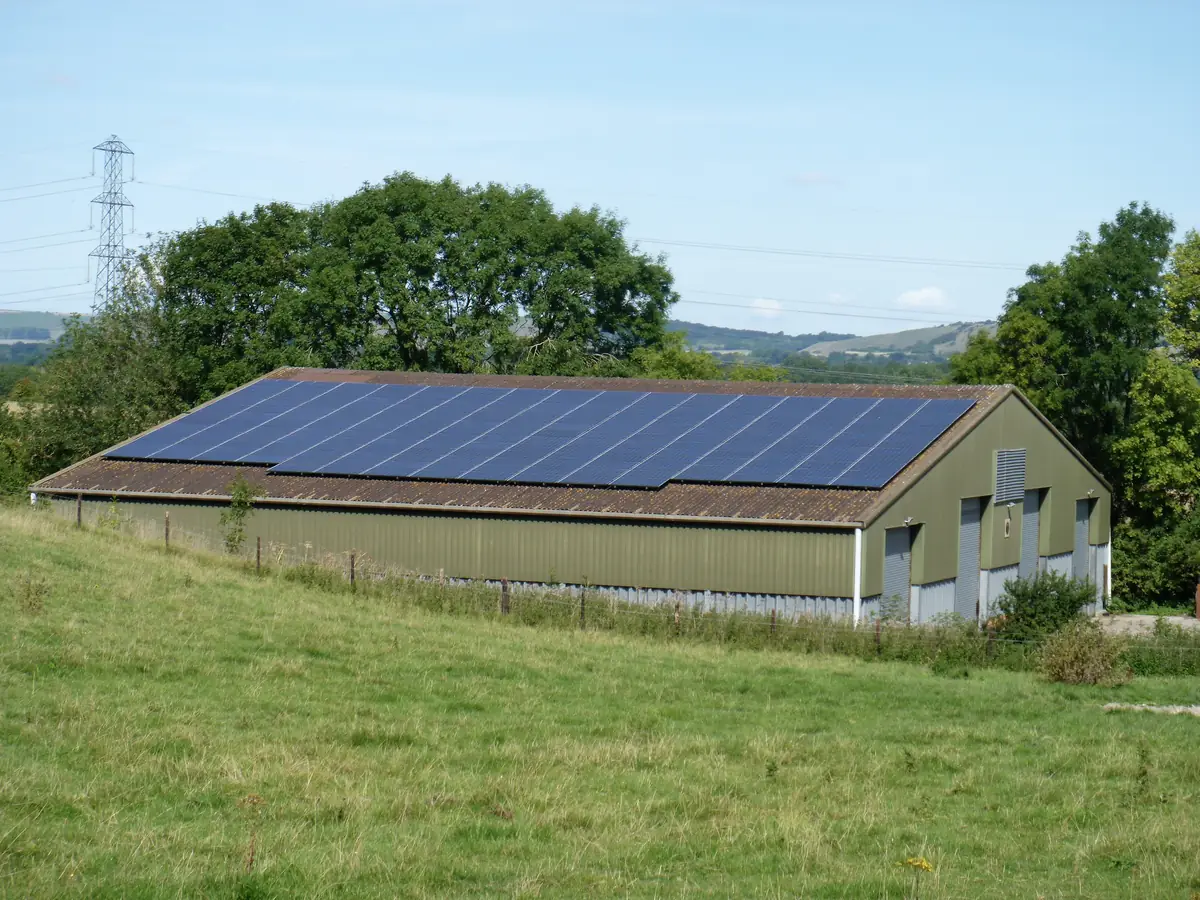 Farm building with a full roof of solar panels in green countryside