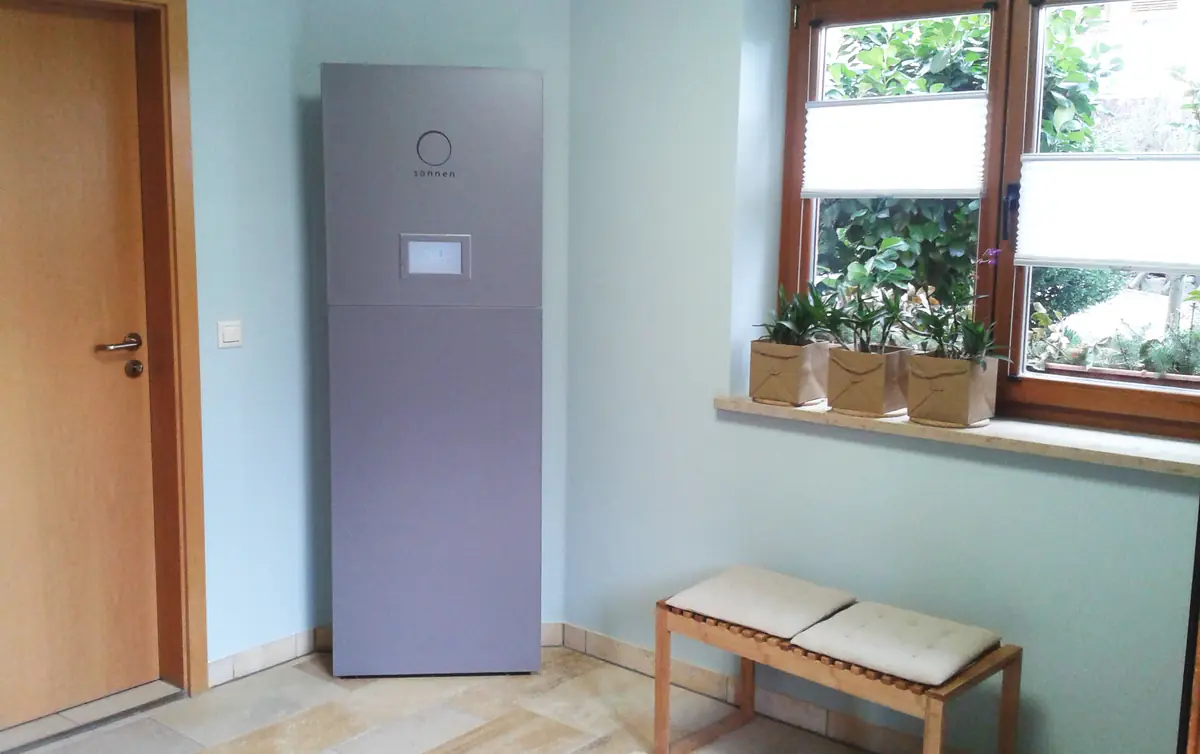 Floor-standing home battery unit against a wall inside a house