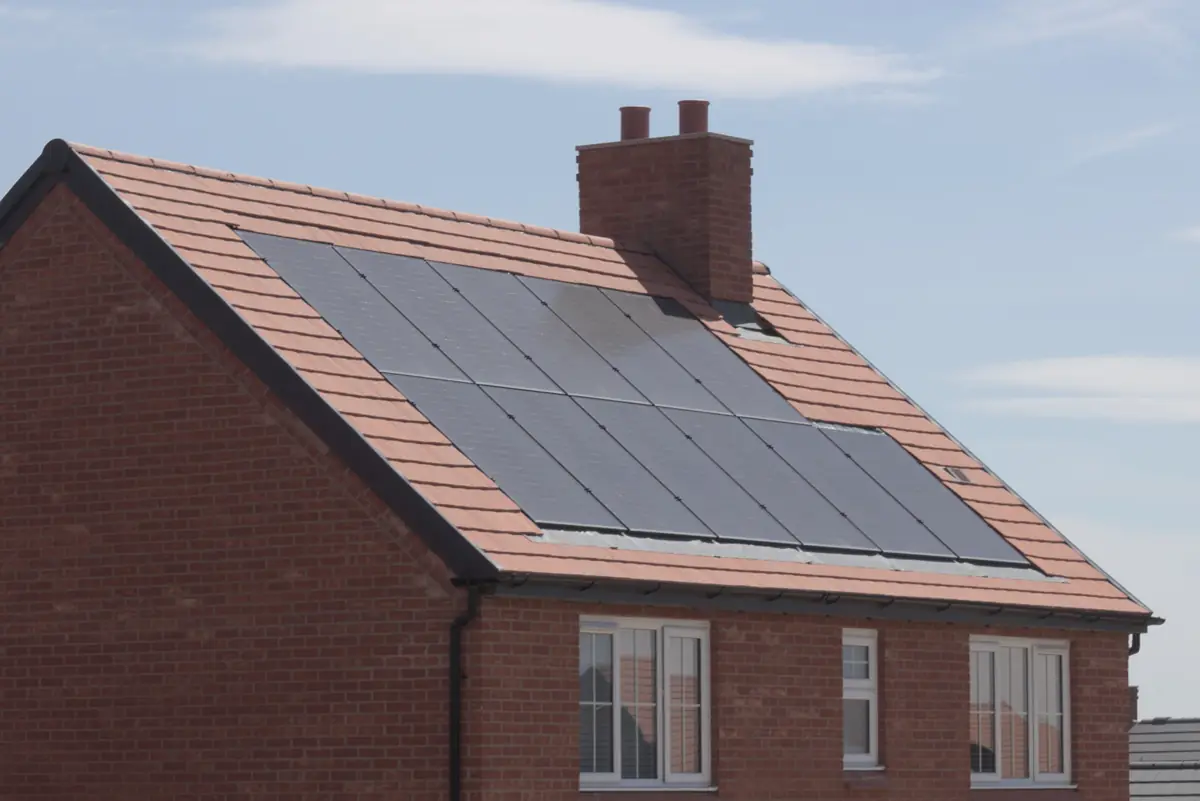 New-build brick house with black solar panels set into a tiled roof