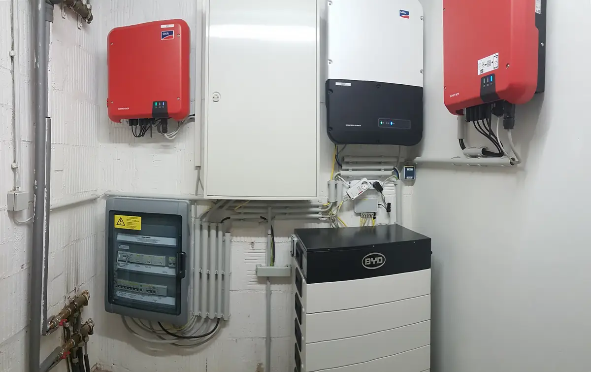 Battery storage stack, inverters and switchgear on a utility room wall